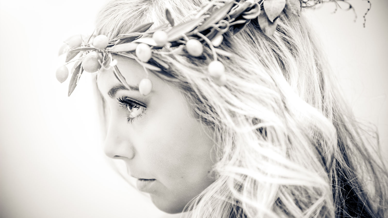 Close-up of pensive bride with olive wreath.