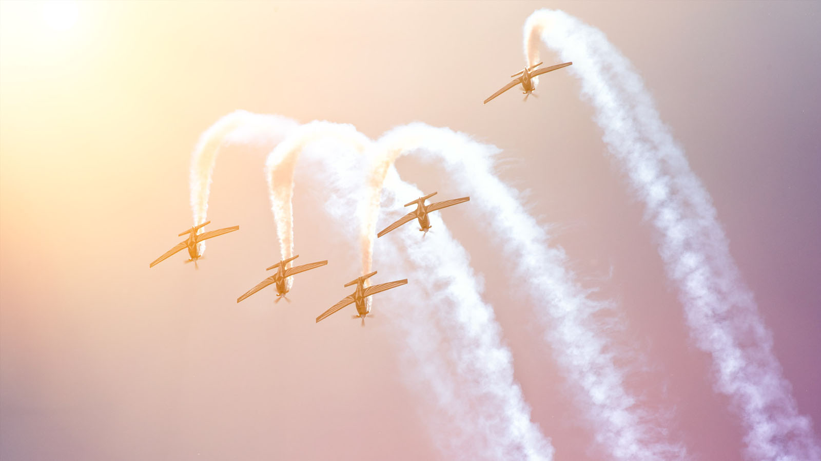 Formation of five inverted aerobatic aircraft.